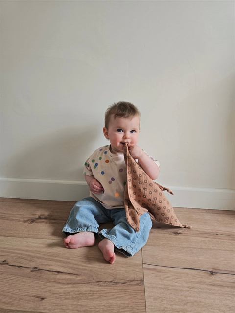 Baby met knuffeldoekje op de grond